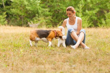 Çimlerin üzerinde oturan kadın evcil hayvanlarına bakarak oynuyor