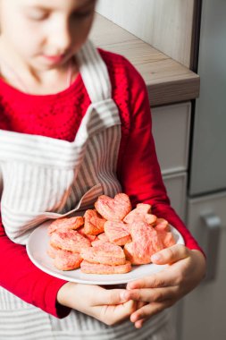 Çocuk elleri tabakta pembe kalp kurabiyetutan