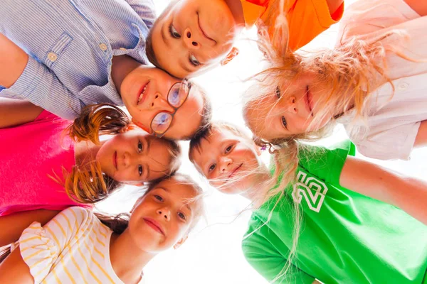 Vrolijke kinderen staan nauw in een cirkel die hun hoofden aanraakt — Stockfoto