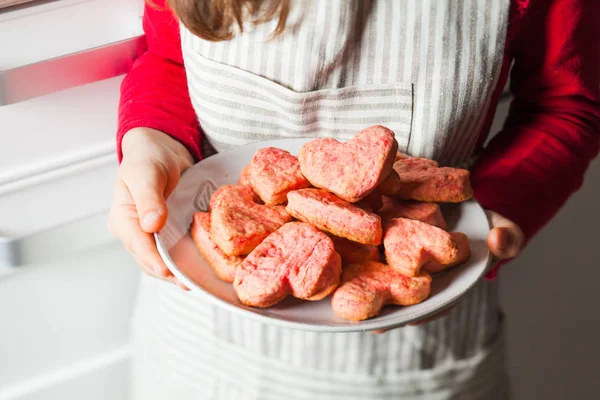 Childs manos sosteniendo galletas de corazón rosa para el día de San Valentín — Foto de Stock