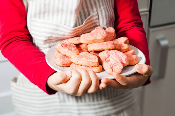 Mani dei bambini che tengono i biscotti al cuore rosa in cucina — Foto Stock