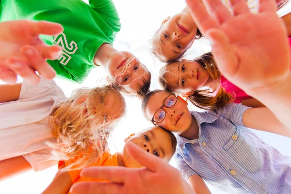 Cheerful kids standing closely in a circle touching their heads Royalty Free Stock Photos