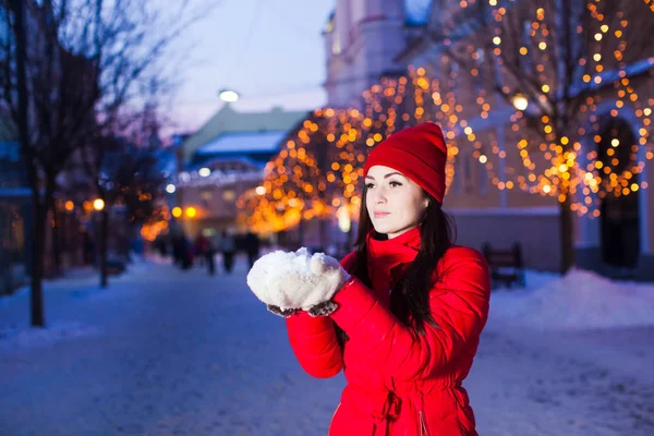 Elegante joven mujer sosteniendo un montón de nieve en sus manos — Foto de Stock