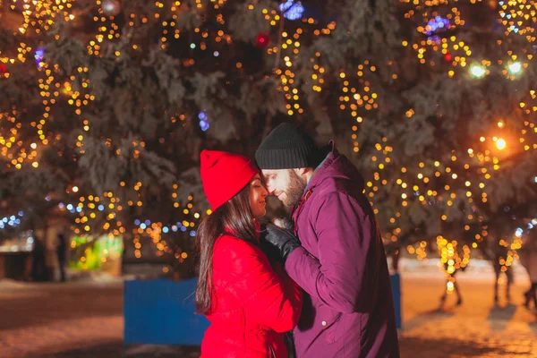 Dulce pareja de pie cara a cara cerca de las luces de Navidad — Foto de Stock