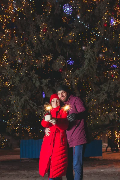 Мужчина и женщина обнимаются под большой елкой — стоковое фото