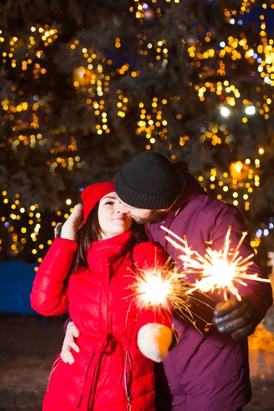 Besos pareja con brillantes luces de bengala al aire libre — Foto de Stock