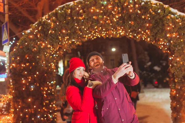 Pareja haciendo selfie cerca de arco decorado con luces — Foto de Stock