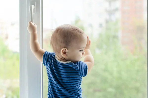 Niño en el alféizar de la ventana, peligro en el hogar —  Fotos de Stock