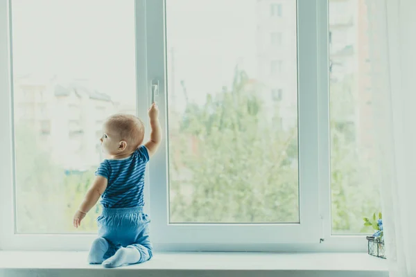 Niño en el alféizar de la ventana, peligro en el hogar —  Fotos de Stock