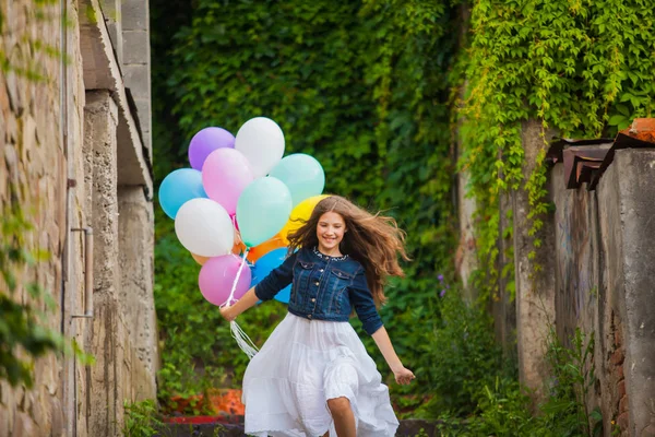 Chica está corriendo con globos de colores al aire libre — Foto de Stock