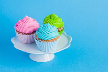 Mavi arka plan üzerinde krem peynir ile Cupcakes