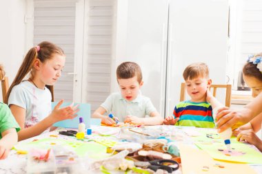 Ana sınıfta anneleri için tebrik kartı yapan çocuklar