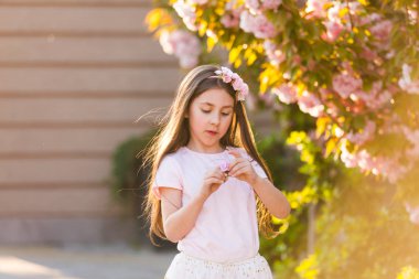 Bahar portre, şapka sevimli küçük kız çiçek ağacında yürümek