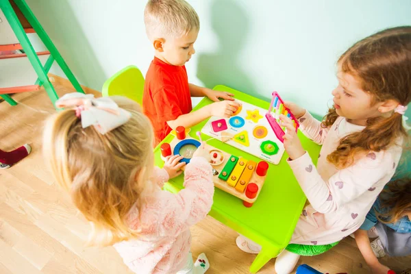 Enfant garçon et filles assis à la table dans la salle de jeux . — Photo