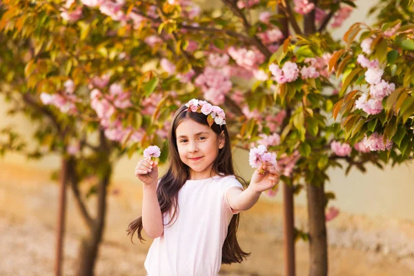 春の肖像画、愛らしい小さな女の子が桜の木の庭を歩く — ストック写真