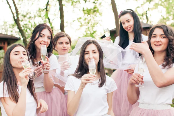 Linda novia y damas de honor felices bebiendo champán en despedida de soltera —  Fotos de Stock