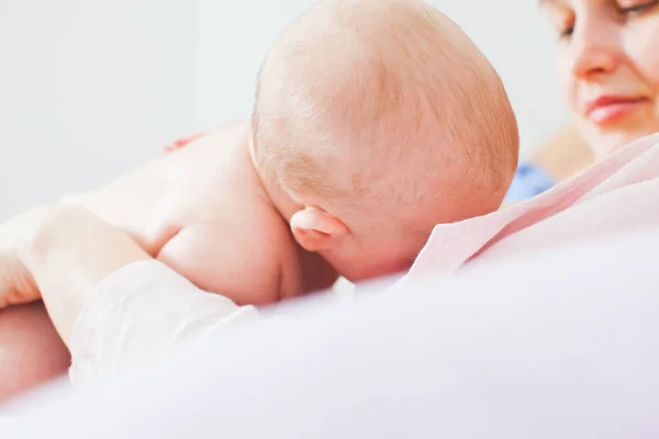 Vista cercana del bebé lactante ligeramente sostenido por la madre — Foto de Stock