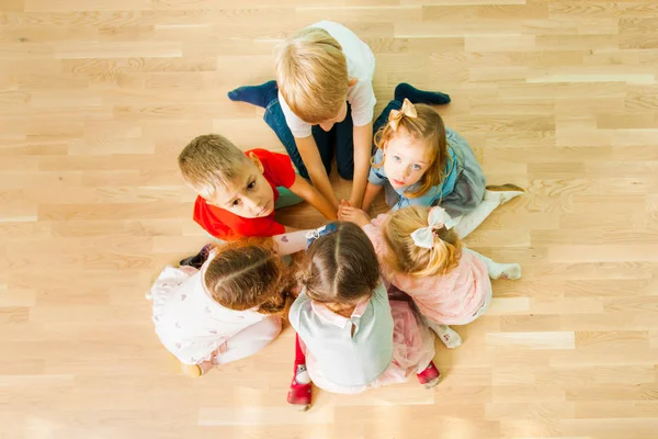 Six enfants assis en cercle, les mains jointes — Photo