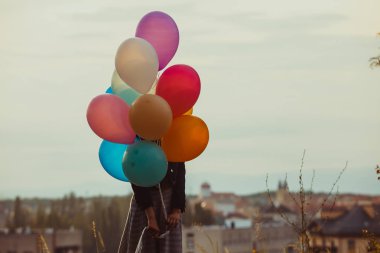 Gün batımında yürüyen renkli balonları olan kız