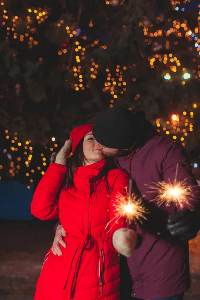 Beijando casal com luzes de bengala espumantes ao ar livre — Fotografia de Stock