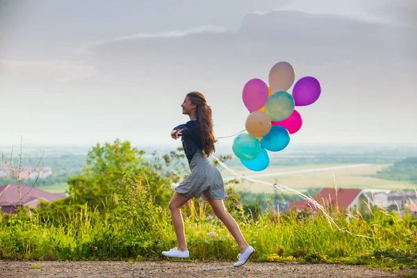 Girl with colorful balloons on the hills — Stock Photo, Image