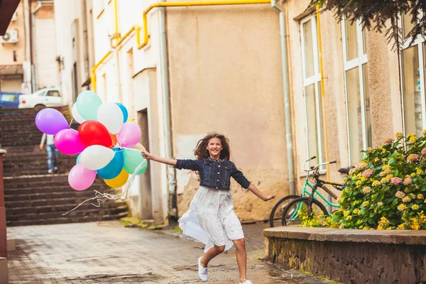 Dívka s pestrobarevné balónky ve městě — Stock fotografie