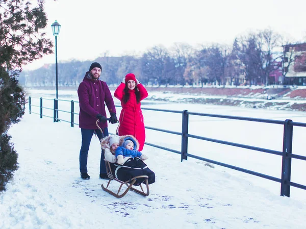 썰매를 타고 부모와 두 아이의 겨울 산책 — 스톡 사진