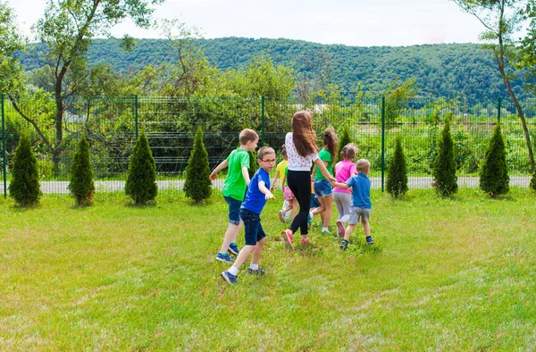 Chłopcy i dziewczęta z nauczycielem grać na podwórku szkolnego — Zdjęcie stockowe