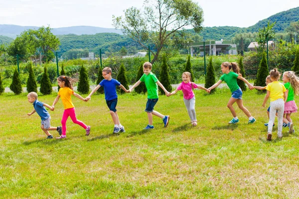 Kinder rennen im Freien Händchen haltend. Mädchen und Jungen haben Spaß — Stockfoto