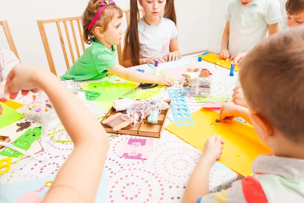 Meninos e meninas sentam-se à mesa e fazem artesanato — Fotografia de Stock