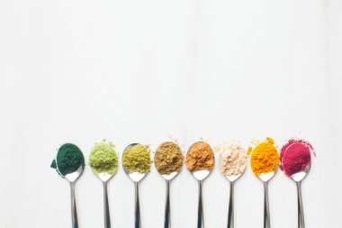 Ahşap masa üzerinde farklı renkli superfood tozlar ile mutfak eşyaları