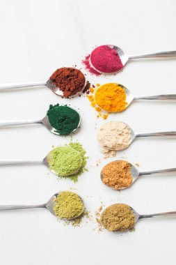 Ahşap masa üzerinde farklı renkli superfood tozlar ile mutfak eşyaları