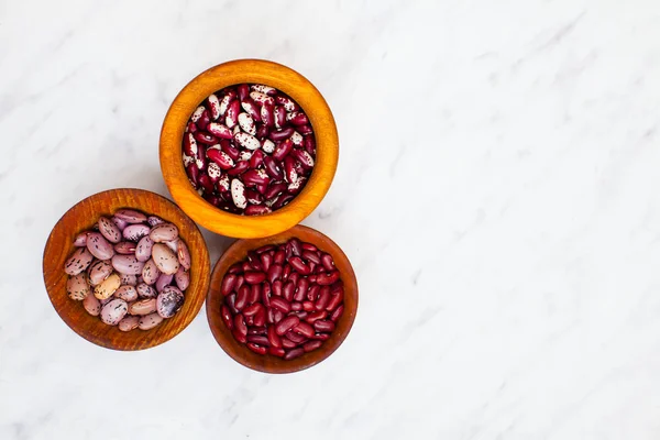 Différents types de haricots rouges dans des bols en bois sur une table — Photo