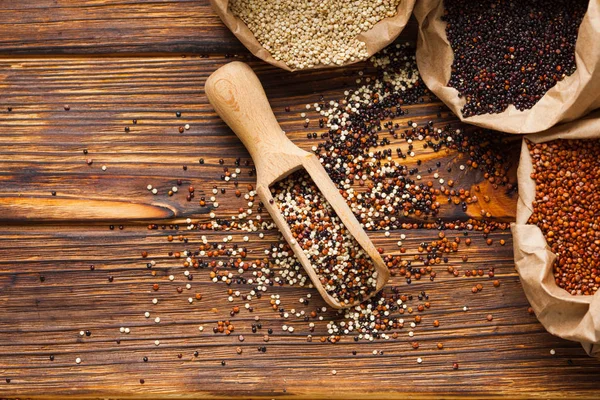 Quinoa w drewnianej szufelka scatterd na drewnianym stole — Zdjęcie stockowe
