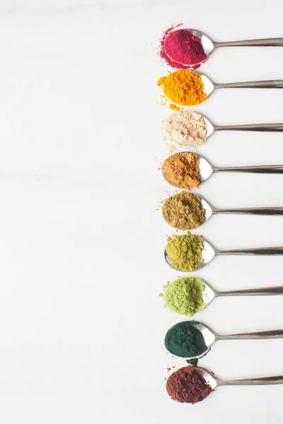 Různé druhy barevných superpotravinových prášků na bílém stole — Stock fotografie
