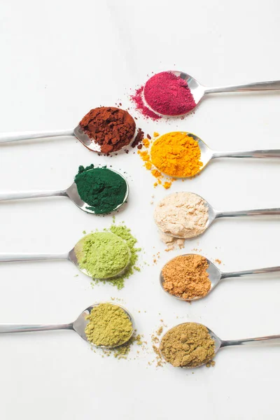 Utensílios de cozinha com diferentes pós coloridos de superalimentos na mesa de madeira — Fotografia de Stock