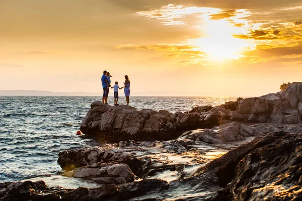 Madre y padre con sus hijos en la puesta del sol del mar —  Fotos de Stock