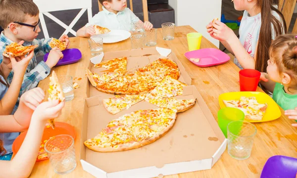 Дети едят пиццу за деревянным столом в номере — стоковое фото