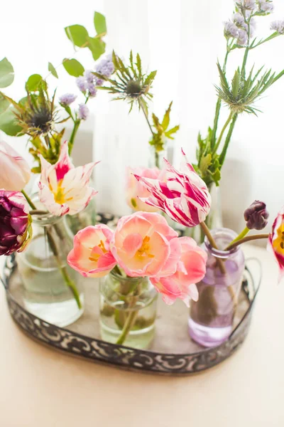 Тюльпаны в стеклянных банках на подносе в белой комнате — стоковое фото