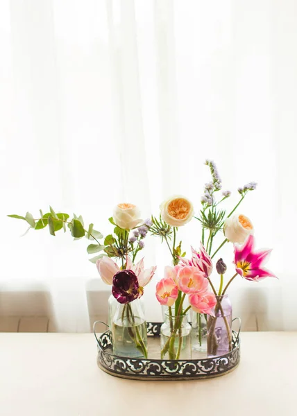 Tulpen in Glasgefäßen auf einem Tablett im weißen Raum — Stockfoto