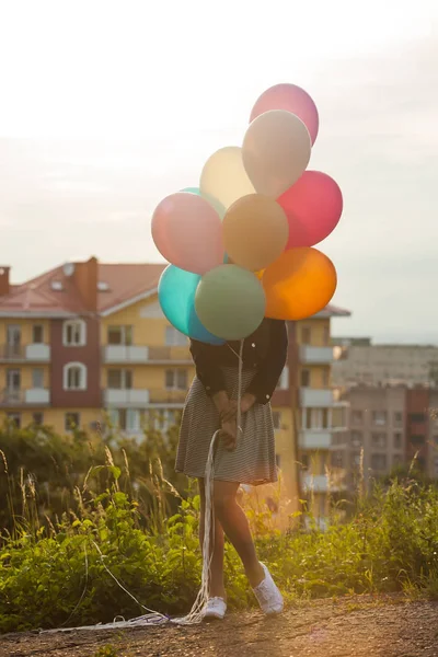 Dívka s pestrobarevné balónky zůstane při západu slunce — Stock fotografie