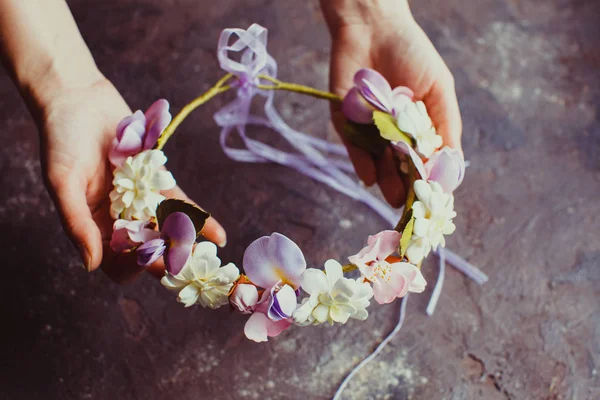 Les femmes mains tiennent une couronne de mousse avec des fleurs de sprint — Photo