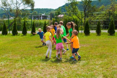 Çocuklar çemberin içinde el ele dans etmeye hazırlanıyorlar.