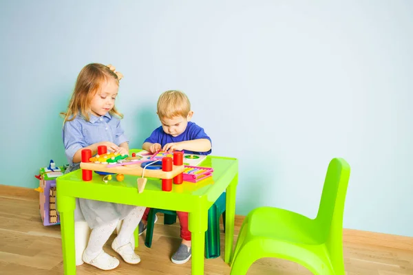 Chłopiec i dziewczyna bawią się przy stole w przedszkolu — Zdjęcie stockowe