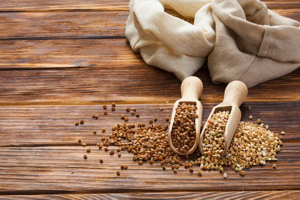 Green and fried buckwheat grains in the wooden scoops — Stock Photo, Image