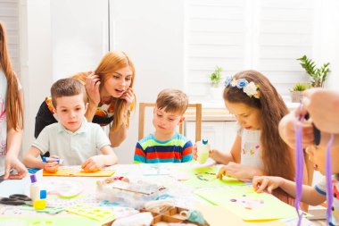 Anne oğullarına el yapımı kartpostallara bakar ve gülümser.