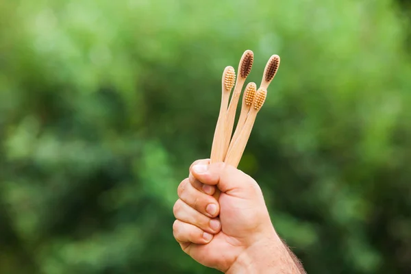 Mano con cepillos de dientes de bambú al aire libre en la naturaleza —  Fotos de Stock