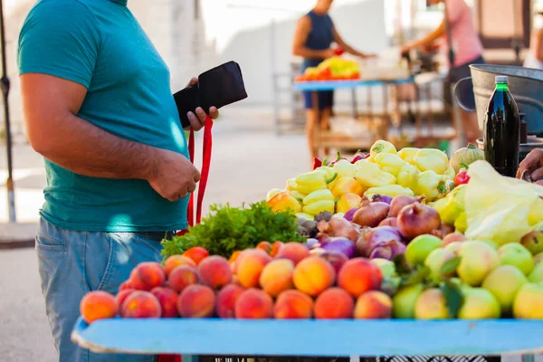 El cliente abre una billetera con dinero para pagar las frutas —  Fotos de Stock