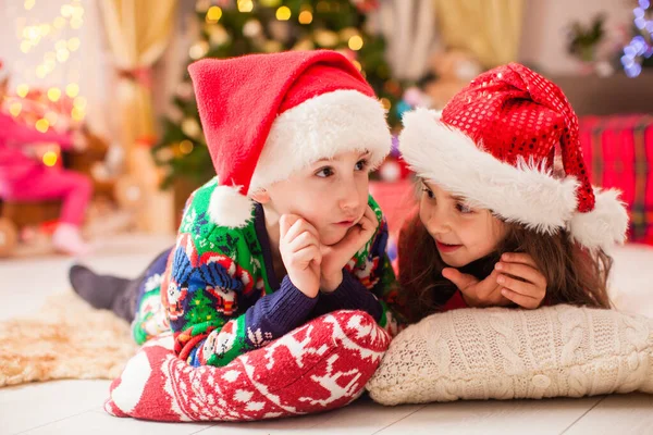 Haar zusje vertelt het winterverhaal aan haar broer. Kinderen dromen over kerstcadeaus — Stockfoto