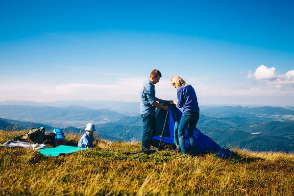 Junge Familie baut ein Zelt auf den Bergen auf. — Stockfoto